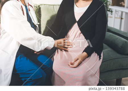 Pregnant woman having her belly examined by a doctor with a stethoscope in a clinic room highlighting a medical checkup, pregnancy health, and prenatal care 139343788