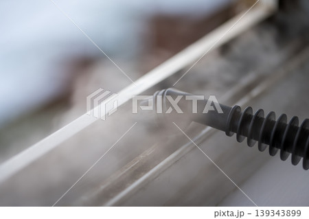 Cleaning the window. Steam device removes dirt from the plastic window frame. Cleaning the window. Steam device removes dirt from the plastic window frame. 139343899