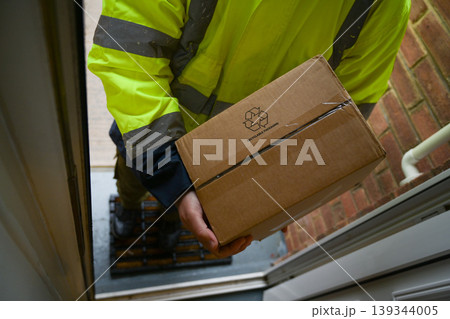 Delivery man at door entrance giving a box to a woman. Online shopping, delivery service 139344005