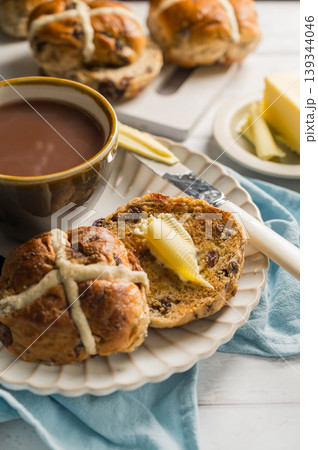 Easter food table setting. Cross Buns with butter, served with tea. Breakfast concept Easter food table setting. Cross Buns with butter, served with tea. Breakfast concept 139344046
