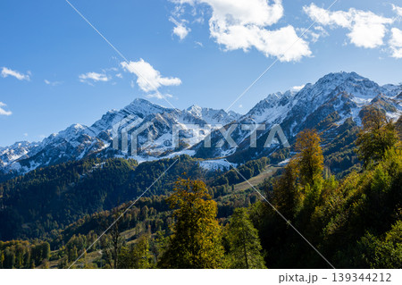 Snow-covered mountains and green trees under blue sky during daytime in a natural setting Snow-covered mountains and green trees under blue sky during daytime in a natural setting 139344212