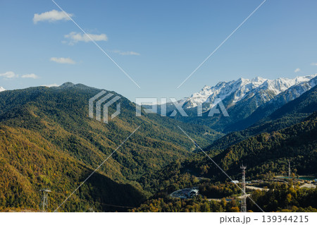 Snow-capped mountains and green valleys under blue sky in Sochi region Snow-capped mountains and green valleys under blue sky in Sochi region 139344215