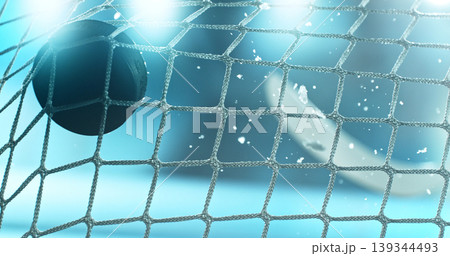 Action sports photo of a hockey puck flying into the goal net during a scoring shot, with ice particles in the air and a hockey stick visible in the background, capturing speed and intensity. Action sports photo of a hockey puck flying into the goal net during a scoring shot, with ice particles in the air and a hockey stick visible in the background, capturing speed and intensity. 139344493