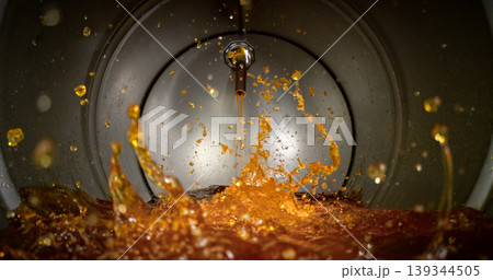 Gasoline jet pouring into metal fuel tank, inside view with dynamic splash and turbulence. Concept of refueling, fuel storage and energy supply, industrial environment. Gasoline jet pouring into metal fuel tank, inside view with dynamic splash and turbulence. Concept of refueling, fuel storage and energy supply, industrial environment. 139344505