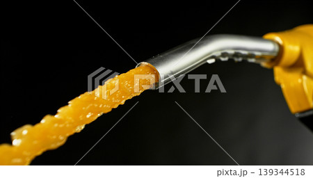 Gasoline jet spraying from fuel nozzle on dark background, no hand visible. Dynamic splash and droplets, refueling concept, energy supply, macro detail, dramatic lighting. Gasoline jet spraying from fuel nozzle on dark background, no hand visible. Dynamic splash and droplets, refueling concept, energy supply, macro detail, dramatic lighting. 139344518