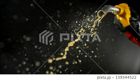 Gasoline jet spraying from fuel nozzle held by hand on dark background. Dynamic liquid motion, refueling concept, energy supply, fuel usage, dramatic lighting, macro detail. Gasoline jet spraying from fuel nozzle held by hand on dark background. Dynamic liquid motion, refueling concept, energy supply, fuel usage, dramatic lighting, macro detail. 139344522