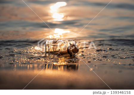 Message in glass bottle on sandy beach at sunset. 139346158
