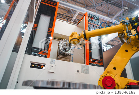 Industrial robotic arm holding metal gear component in automated factory cell. Industrial robotic arm holding metal gear component in automated factory cell. 139346168