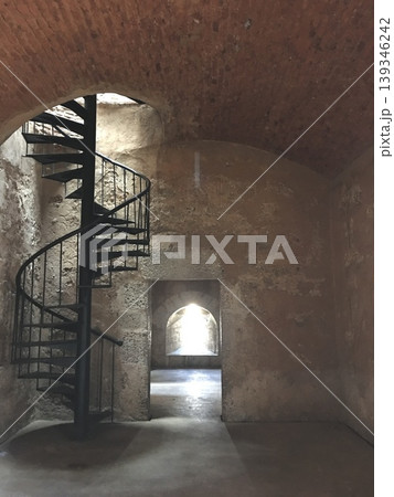 Spiral staircase in historic stone interior with soft natural light, clean architectural background 139346242