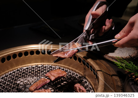 炭火焼肉グリルで焼かれる牛肉スライスとトングのクローズアップ 炭火焼肉グリルで焼かれる牛肉スライスとトングのクローズアップ 139346325