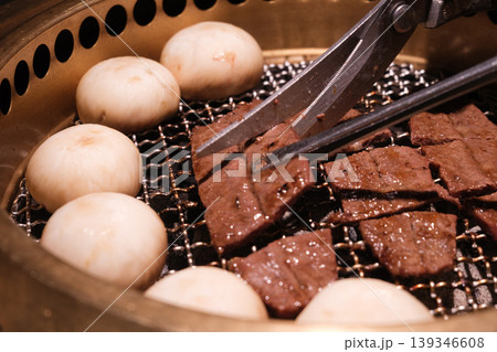 炭火焼肉グリルで焼かれる牛肉スライスとトングのクローズアップ 炭火焼肉グリルで焼かれる牛肉スライスとトングのクローズアップ 139346608