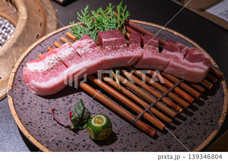 焼肉レストランで提供される黒いセラミックプレートに盛られた生の豚バラ肉の精巧な盛り付け 焼肉レストランで提供される黒いセラミックプレートに盛られた生の豚バラ肉の精巧な盛り付け 139346804