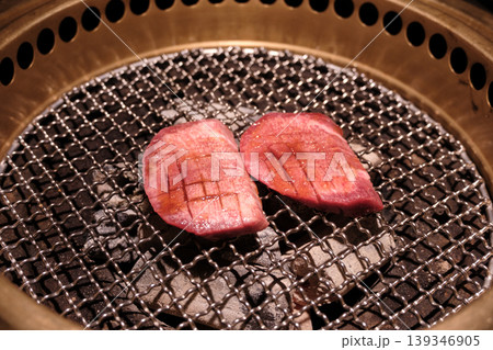 炭火焼肉グリルに乗せた厚切り牛タンの切り込み入り生肉クローズアップ 炭火焼肉グリルに乗せた厚切り牛タンの切り込み入り生肉クローズアップ 139346905