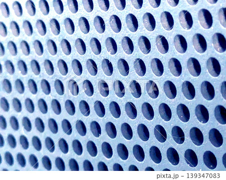Close-up of shiny perforated metal surface with blurred background and patterned holes Close-up of shiny perforated metal surface with blurred background and patterned holes 139347083