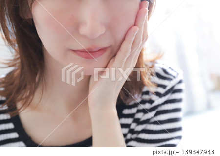 頬を押さえて歯の痛みに耐える女性 頬を押さえて歯の痛みに耐える女性 139347933
