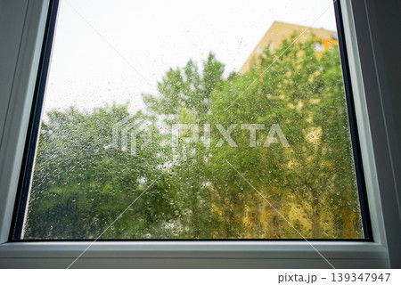 Raindrops on a window pane showing greenery n the background on a cloudy day Raindrops on a window pane showing greenery n the background on a cloudy day 139347947