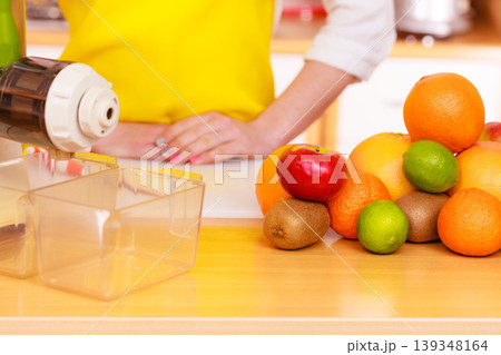 Woman in kitchen preparing fruits for juicing Woman in kitchen preparing fruits for juicing 139348164