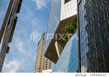 Modern glass building with cantilever structure and urban greenery Modern glass building with cantilever structure and urban greenery 139348223