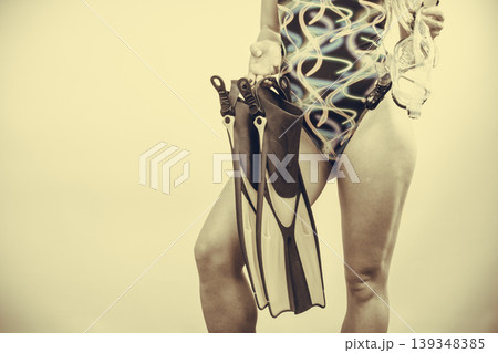 Woman in swimsuit holds flippers 139348385