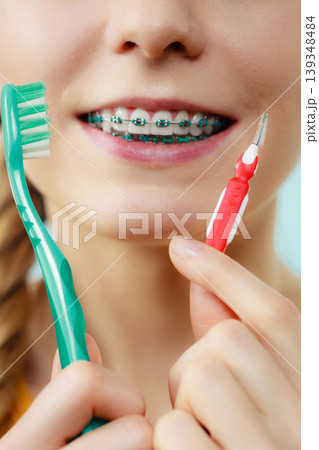Girl with teeth braces using interdental and traditional brush 139348484