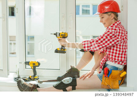 Woman using drill on window Woman using drill on window 139348497