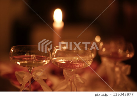 Elegant champagne glasses with ribbons on a table, soft candlelight creating a warm ambiance, blurred background highlights romantic setting for special occasions 139348977