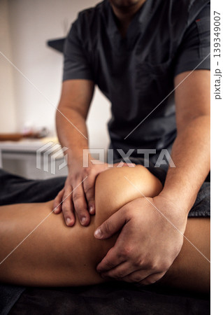 Male massage therapist providing therapeutic treatment to a female client on a massage table, focusing on relaxation and wellness in a serene environment with soft lighting 139349007
