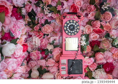 Antique pink analog telephone set on wall in pink roses and flowers 139349444