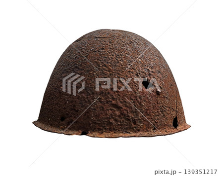 The image shows a soldier's helmet that has rusted with age. It has visible bullet holes. The helmet stands out against a white background, highlighting its worn condition. The image shows a soldier's helmet that has rusted with age. It has visible bullet holes. The helmet stands out against a white background, highlighting its worn condition. 139351217