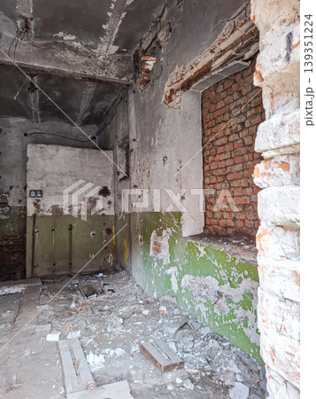 The room shows crumbling plaster walls and exposed red bricks. Debris is scattered on the floor. The space has not been used for a long time. There are signs of decay and neglect. 139351224