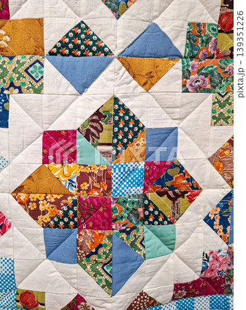 A mix of colorful fabrics in floral and geometric patterns. The design forms a star shape. It displays handmade craft and textile art with various colors and textures. A mix of colorful fabrics in floral and geometric patterns. The design forms a star shape. It displays handmade craft and textile art with various colors and textures. 139351226