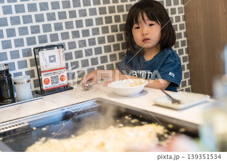 鉄板焼き店でもんじゃ焼きを食べる日本人の女の子の幼児 鉄板焼き店でもんじゃ焼きを食べる日本人の女の子の幼児 139351534