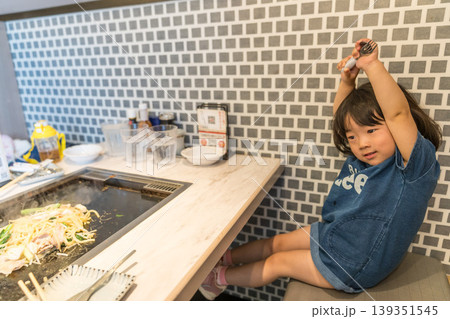 鉄板焼き店でもんじゃ焼きを食べる日本人の女の子の幼児 139351545