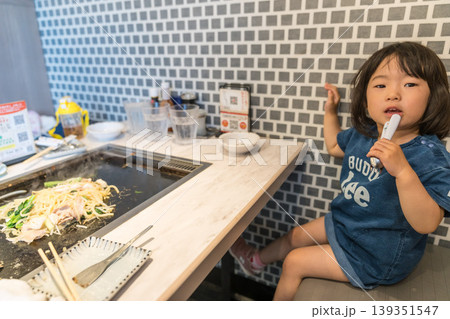 鉄板焼き店でもんじゃ焼きを食べる日本人の女の子の幼児 鉄板焼き店でもんじゃ焼きを食べる日本人の女の子の幼児 139351547