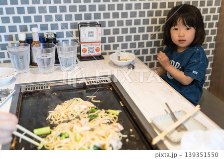 鉄板焼き店でもんじゃ焼きを食べる日本人の女の子の幼児 鉄板焼き店でもんじゃ焼きを食べる日本人の女の子の幼児 139351550