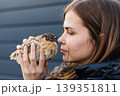Young woman holds a quail in her hands, touching her nose to its beak. The connection between man and nature. 139351811