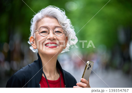 スマホを持ち大きく笑うシニア女性のクローズアップ スマホを持ち大きく笑うシニア女性のクローズアップ 139354767