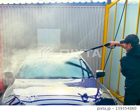 A man washes a car at a self-service car wash. Car wash concept 139354860
