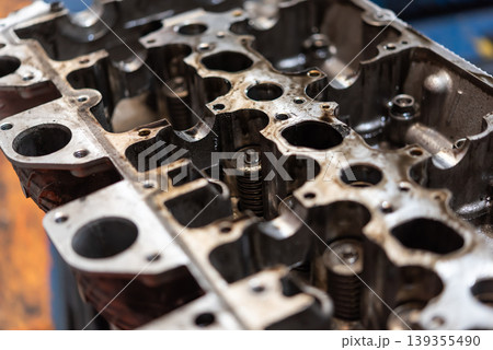 Detailed closeup of engine cylinder head showing ports valves and metal surfaces highlighting automotive repair maintenance and precision engineering components Detailed closeup of engine cylinder head showing ports valves and metal surfaces highlighting automotive repair maintenance and precision engineering components 139355490