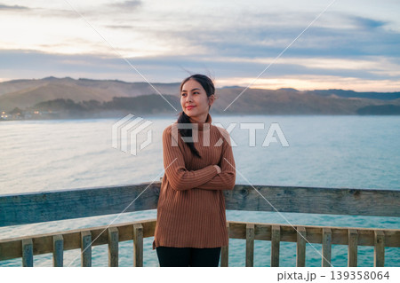 Woman posing on lighthouse by pacific ocean in the evening at New Zealand Woman posing on lighthouse by pacific ocean in the evening at New Zealand 139358064
