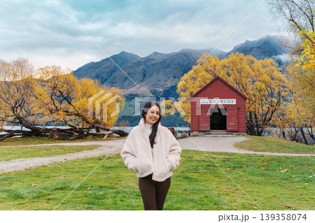 Asian woman traveling in Glenorchy with red boatshed by Lake Wakatipu on autumn at New Zealand 139358074