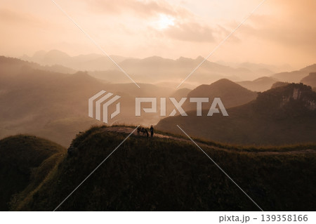 Sunrise over Ba Guang grass hill, Mountain range and fog along with villager bringing their horse to graze on the mountain Sunrise over Ba Guang grass hill, Mountain range and fog along with villager bringing their horse to graze on the mountain 139358166