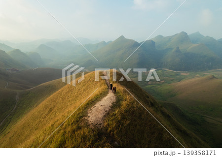 Aerial view of Ba Guang grass hill, Mountain range with fog and villager bringing horse to graze on the mountain in the morning 139358171