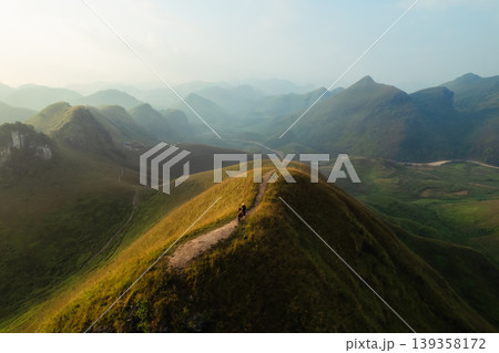 Aerial view of Ba Guang grass hill, Mountain range with fog and villager bringing horse to graze on the mountain in the morning Aerial view of Ba Guang grass hill, Mountain range with fog and villager bringing horse to graze on the mountain in the morning 139358172