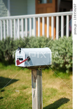 White american mailbox set on wooden post at front of house 139358207