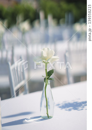 Elegant wedding long table with candle, white rose flower and white chairs in the garden 139358215