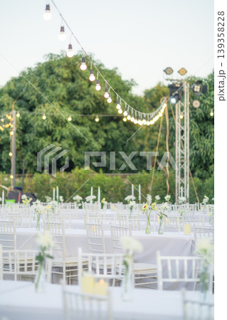 Elegant wedding long table with candle, white rose flower and white chairs in the garden 139358228