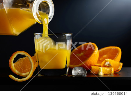 Glass of orange juice with ice on a black background. Glass of orange juice with ice on a black background. 139360014