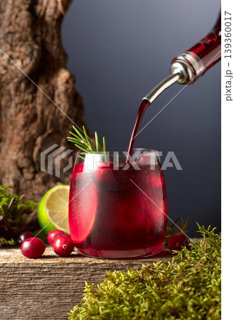 Cranberry cocktail with ice, lime, and rosemary on a old wooden board. Cranberry cocktail with ice, lime, and rosemary on a old wooden board. 139360017