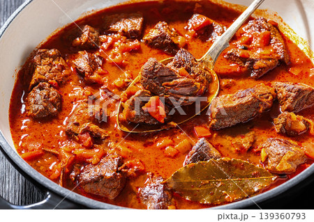 Spoon picking beef chunk from goulash stew 139360793